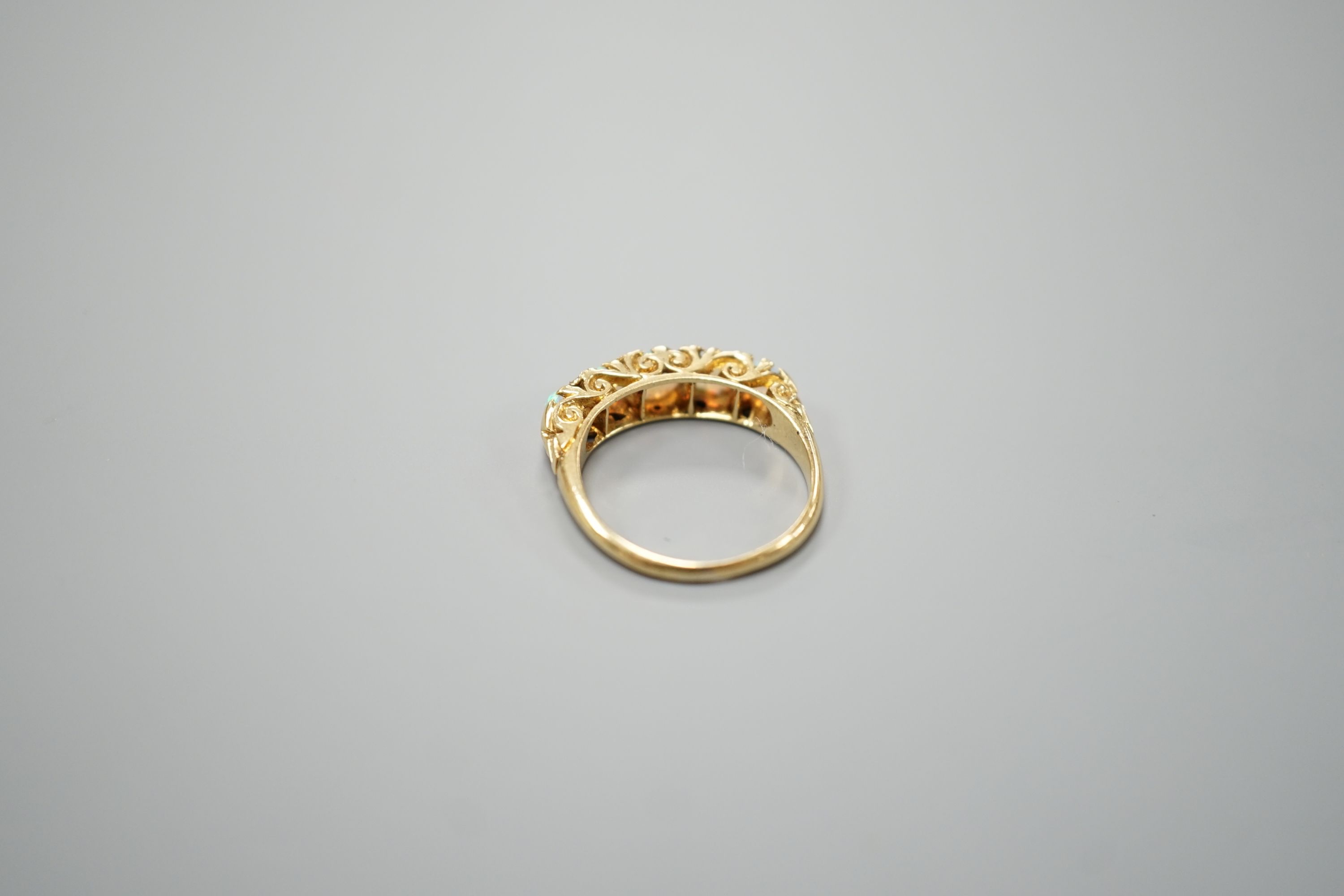 A late Victorian yellow metal and graduated five stone white opal set half hoop ring, with diamond chip spacers, size M, gross weight 3.7 grams.